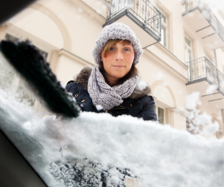 Woman cleaning snow off windshield - your own garage, the American Dream